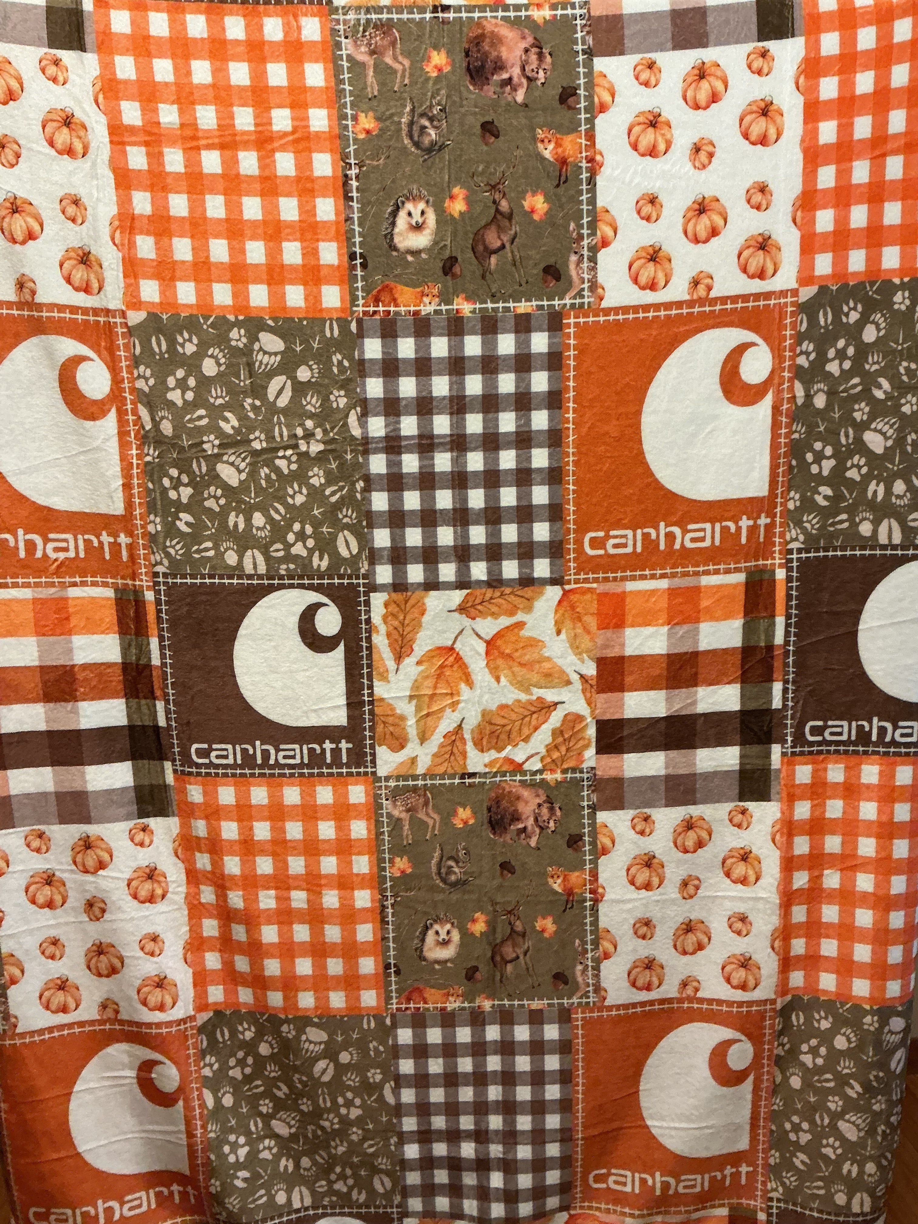 Patchwork print featuring Carhartt fabric squares in orange, brown, white, and gray, with gingham, floral, and leaf patterns.