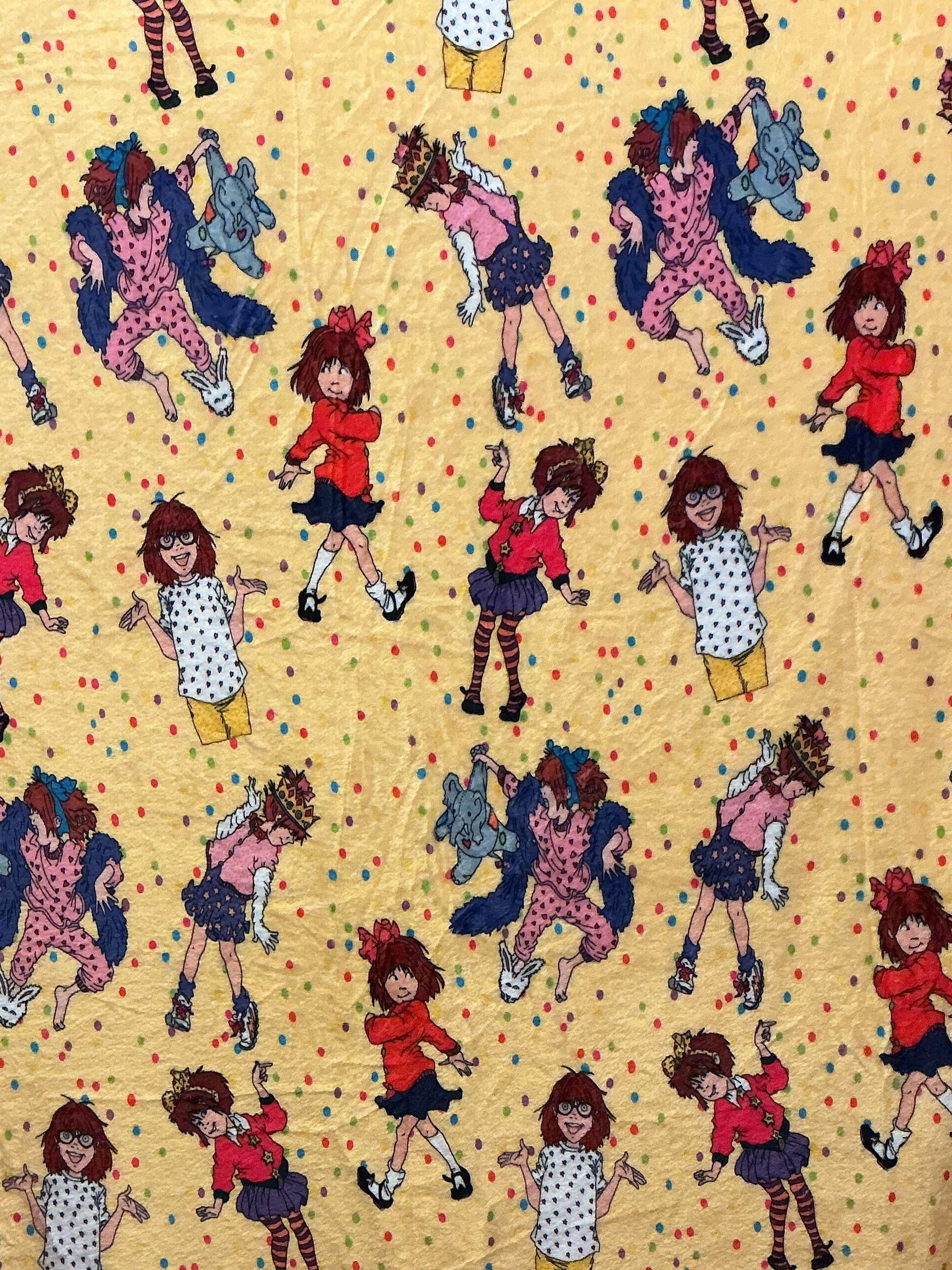 Book character Junie B Jones in colorful outfits scattered across a pale yellow background with small multicolored dots.
